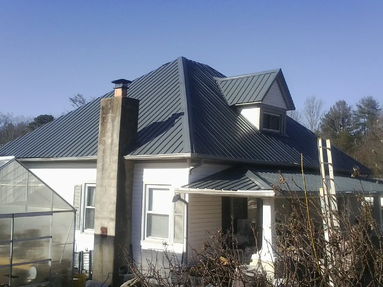Dark blue standing seam metal roof on a white farmhouse with dormer — Slate & Tile Roof Repair by Roofing Brothers in Redondo Beach
