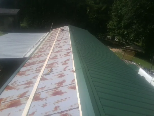 Old rusted panels beside newly installed green metal roofing — Wind Damage Roof Repair by Roofing Brothers in Redondo Beach