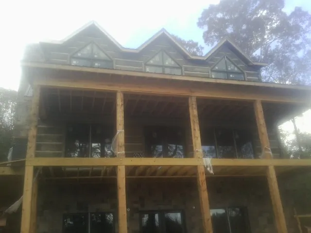Dormers and porch framing on a large log home under construction — Roof Coating work by our crew in Redondo Beach