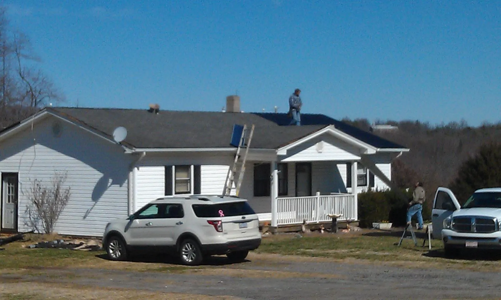 Roofers stripping shingles from a white ranch house roof in Redondo Beach
