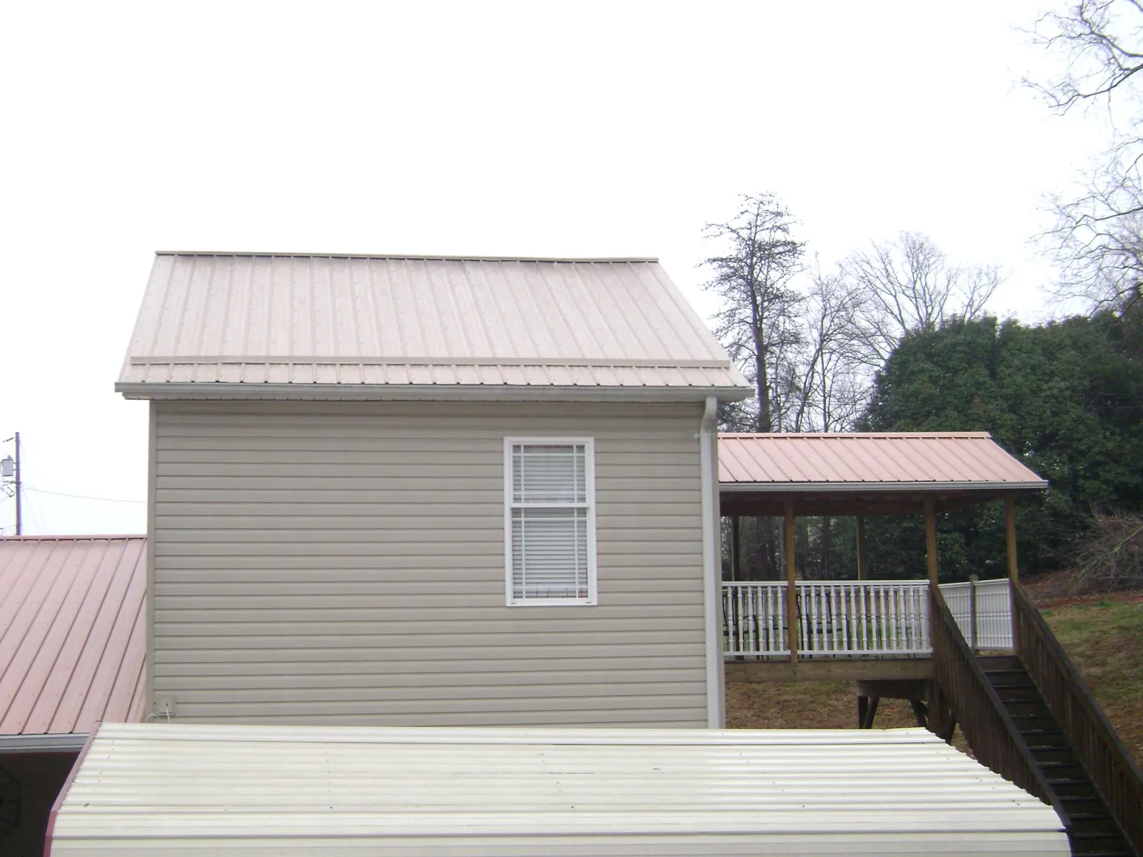 Tan metal roofs on a two story addition and attached porch, from a Roof Replacement job in Redondo Beach